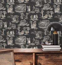 Black takai wallpaper featuring pastoral scenes. A sleek wooden table with a stylish lamp and stacked books.
